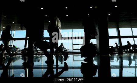 à l'aéroport, dans la salle d'attente, sur le fond de la fenêtre donnant sur les avions et la piste, les silhouettes marchent, ils se précipitent sur leurs vols. Photo de haute qualité Banque D'Images