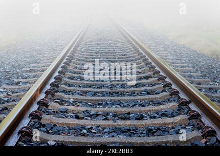 Les voies de chemin de fer abandonnées disparaissent dans l'épais mur de brouillard. Banque D'Images