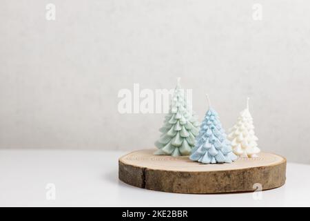 Bougies décoratives faites à la main en cire de soja naturelle sous forme d'arbre de Noël aux couleurs bleu, vert et blanc sur un support en bois Banque D'Images