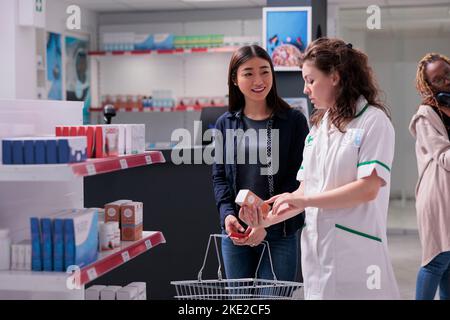 Pharmacien aidant le client à recommander un produit donnant des conseils pharmaceutiques en pharmacie. Spécialiste en pharmacie consultant le client avant de vendre des suppléments. Boutique pharmaceutique Banque D'Images