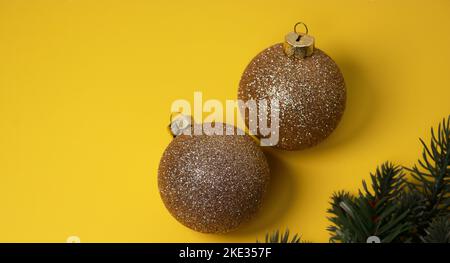 boules décoratives de Noël dorées sur fond jaune avec pin vert Banque D'Images