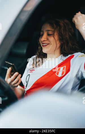 Fan péruvien de football réagissant avec enthousiasme à un match de football en regardant son téléphone cellulaire. Concept de personnes et de sports. Banque D'Images