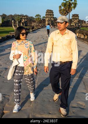 Un guide officiel du temple antique d'Angkor Wat au Cambodge parle avec un touriste vietnamien sur la chaussée ouest du monument. Banque D'Images