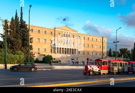 La façade du Parlement hellénique (grec), située dans l'ancien palais royal surplombant la place Syntagma et le bus à arrêts multiples du Happy train d'Athènes. Banque D'Images