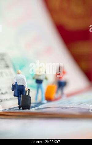 Création d'un studio de concept de jouets miniatures - un homme d'affaires expatrié tirant un bagage arrive ou part avec des timbres de passeport de visa comme arrière-plan. Banque D'Images