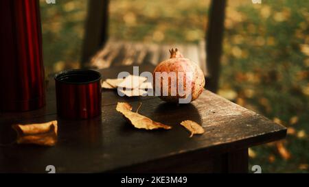 Thermos, mug et grenade parmi les feuilles d'automne sur une ancienne table en bois Banque D'Images