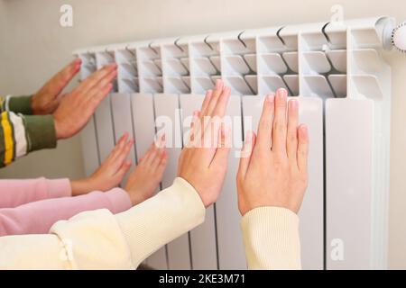 La famille chauffe ses mains près du radiateur. Banque D'Images