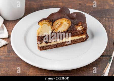 Gâteau avec profiteroles sur une assiette en porcelaine blanche avec café filtre sur le côté Banque D'Images