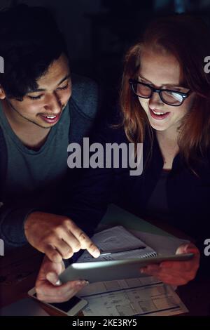 Cela ne leur dérange pas de faire du travail supplémentaire. Un groupe de jeunes travaillent tard dans le bureau. Banque D'Images