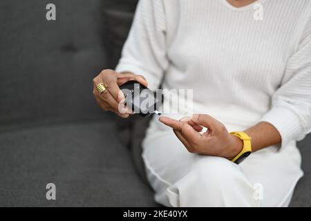 Femme d'âge moyen vérifiant les niveaux de glucose sanguin à l'aide d'un glucomètre. Diabète et concept de soins de santé Banque D'Images