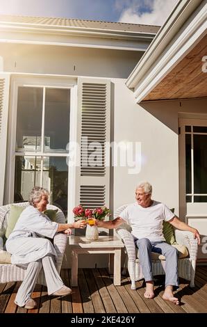 Heres au début d'un chapitre relaxant. Un couple heureux de personnes âgées qui toasque avec du jus sur le patio à la maison. Banque D'Images