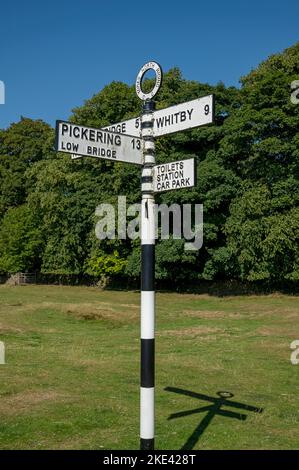 Ancien panneau de signalisation en métal indiquant les directions vers Whitby et Pickering en été Goathland North Yorkshire Angleterre Royaume-Uni Grande-Bretagne Banque D'Images