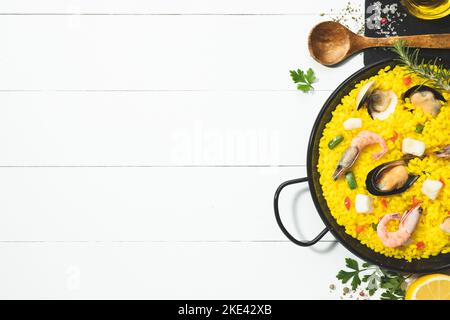 Paella de fruits de mer sur une poêle traditionnelle paella sur une base en bois blanc avec espace de copie. Vue du dessus. Banque D'Images