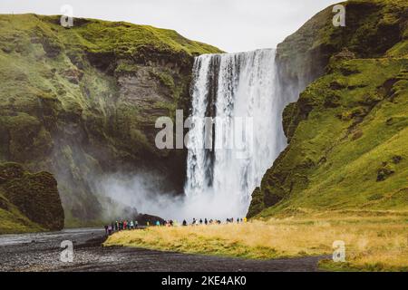 Célèbre cascade de Skogafoss sur la rivière Skoga - touristes se tenant devant et regardant la chute d'eau Banque D'Images