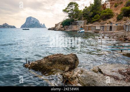 La plage à es Vedra avec des garages pour bateaux et un ciel nuageux en arrière-plan, l'Espagne Banque D'Images