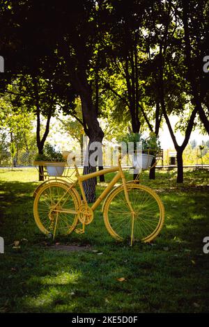 Lit de fleurs de vélo. Stand décoratif en forme de vélo vintage avec fleurs jaunes dans le parc d'automne en octobre. Mise au point sélective Banque D'Images