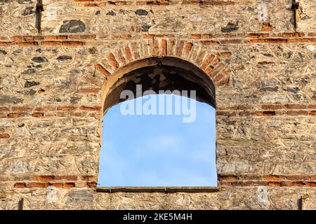 fenêtre ovale dans un bâtiment en brique qui s'ouvre sur le ciel, fenêtre ronde ancienne, pouf ancien Banque D'Images