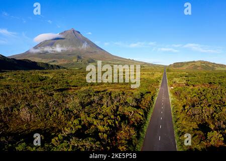 Vue aérienne d'une route passant Ponta da Pico partiellement couverte de nuages avec ciel clair près de Lagoa do Capitão, île de Pico, Açores, Portugal Banque D'Images