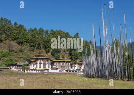 Vue sur le paysage des bannières de prière bouddhistes traditionnelles avec le temple de Kurjey lhakhang complexe en arrière-plan dans la vallée de Bumthang, Bhoutan Banque D'Images