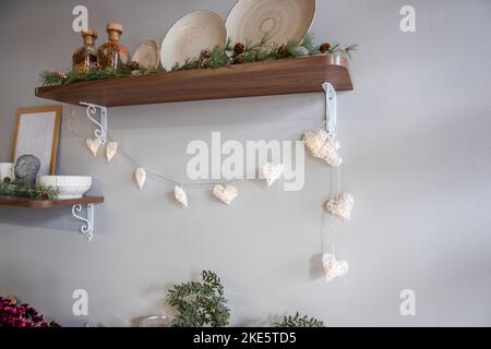 Décoration de cuisine élégante et concise pour Noël. Étagères en bois avec assiettes, décorées avec une guirlande et des branches d'épinette. Minimalisme à la mode Banque D'Images