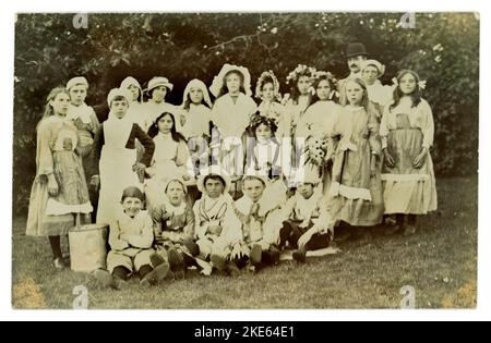 Carte postale originale du début des années 1900 d'un groupe d'enfants à l'extérieur portant une robe de fantaisie, un homme semble être habillé comme Charlie Chaplin ou pourrait juste être la mode du jour. Vers 1919 Royaume-Uni Banque D'Images