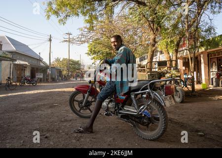 Mtowambu, Tanzanie - 12 octobre 2022 : un motard qui montre son vélo dans la rue principale de la petite ville de Mtowambu, Tanzanie. Banque D'Images