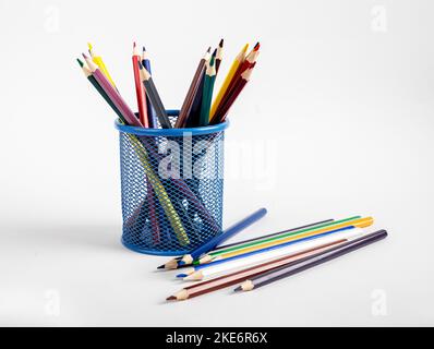 Crayons de couleur différente dans support en métal et fournitures de dessin éparpillées. Photo de haute qualité Banque D'Images