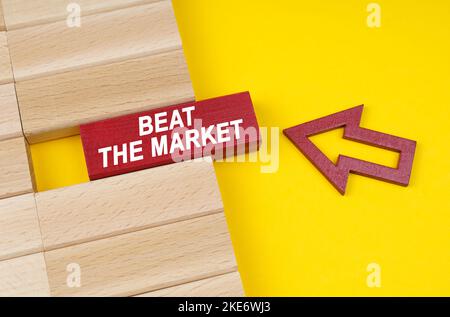 Concept d'entreprise. Sur une surface jaune se trouvent des blocs de bois et une flèche pointant vers un bloc avec l'inscription - Beat the Market Banque D'Images