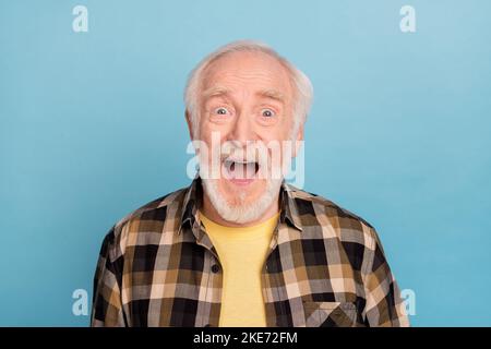 Photo de joli impressionné homme retraité porter chemise à carreaux sourire bouche ouverte isolé couleur bleue fond Banque D'Images