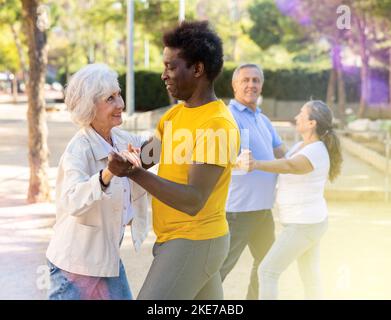Des amis adultes souriants et heureux dansent en couple dans le jardin Banque D'Images