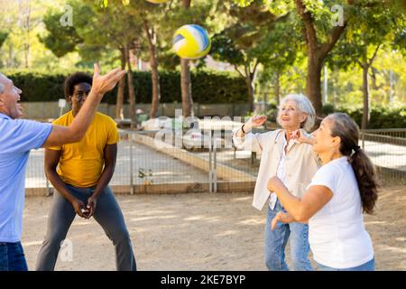 Joyeux groupe multiracial de personnes adultes adultes adultes jouant au volley-ball en plein air Banque D'Images