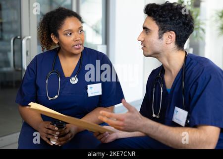 Divers médecins féminins et masculins avec dossier assis dans la discussion à l'hôpital Banque D'Images