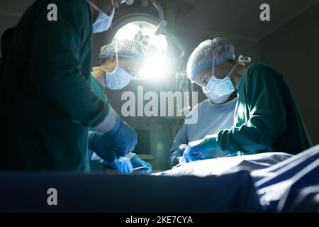 Divers groupes de chirurgiens féminins et masculins opérant sur des patients dans le bloc opératoire Banque D'Images