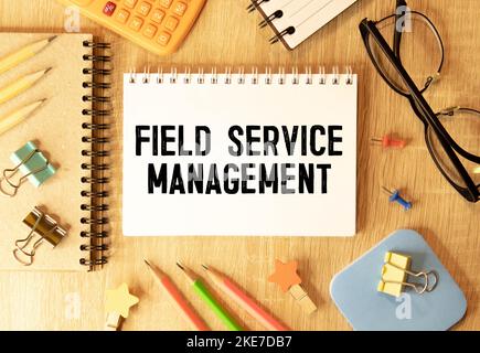 Sur fond bleu clair, des blocs et cubes en bois clair avec le texte FSM Field Service Management. Banque D'Images