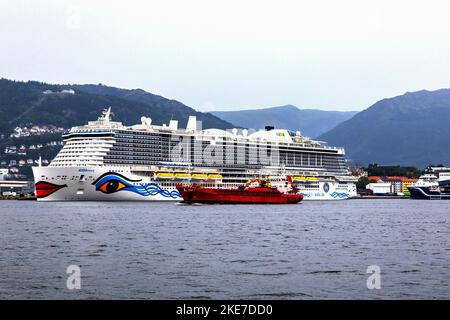 Bateau de croisière Sky AIDAnova au terminal de Jekteviken dans le port de Bergen, Norvège. Préparation pour le départ. Ancien cargo général Dantic passant à l'intérieur Banque D'Images