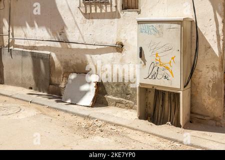 Boîtier de commande électrique avec graffiti dans une rue sale et un mur latéral de bâtiment. Banque D'Images