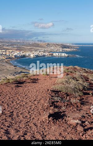 Terrain volcanique rouge avec une flore endémique rare au sommet de la montagne Montana Roja avec vue sur la ville côtière connue sous le nom d'El Medano Banque D'Images