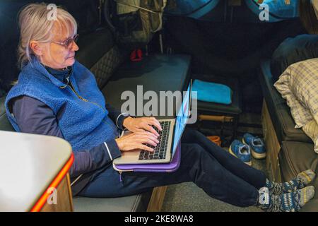 Femme senior travaillant sur ordinateur portable à l'intérieur d'Airstream Interstate 24X 4WD campervan; Morgan's Landing State Recreation site; Kenai Peninsula; Sterling; Alask Banque D'Images