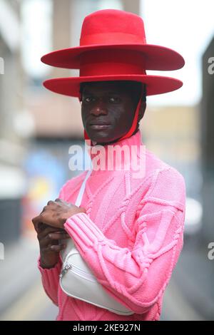 Homme en chapeau portant un pull rose dans une rue de l'est de Londres, Royaume-Uni Banque D'Images