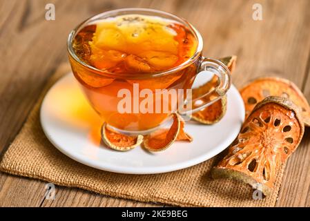 Thé Bael sur verre avec tranches de bael séchées sur fond de bois, jus de Bael - thé sec aux fruits de bael pour la santé - Aegle marmelos Banque D'Images