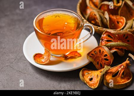 Thé Bael sur verre avec tranches de bael séchées sur fond sombre, jus de Bael - thé sec aux fruits Bael pour la santé - Aegle marmelos Banque D'Images