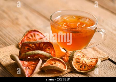 Thé Bael sur verre avec tranches de bael séchées sur fond de bois, jus de Bael - thé sec aux fruits de bael pour la santé - Aegle marmelos Banque D'Images