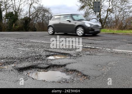 Fichier non daté photo d'une voiture passant des nids-de-poule dans une route près de Peterborough à Cambridgeshire. Trois conducteurs sur cinq (60 %) croient que l'état des routes locales s'est détérioré au cours de la dernière année, suggère une nouvelle étude. Seulement 4 % des 3 102 automobilistes interrogés pour le RAC ont déclaré que les routes de leur région se sont améliorées. Date de publication : vendredi 11 novembre 2022. Banque D'Images