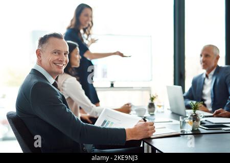 Shes fait un excellent travail. Portrait d'un homme d'affaires assis dans une salle de réunion avec des collègues. Banque D'Images