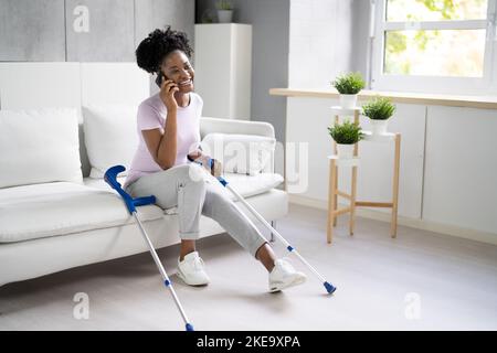 Femme atteinte d'une jambe en utilisant des béquilles à la maison Banque D'Images