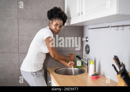 Nettoyage de l'évier et de l'évacuation obstrués dans la cuisine à l'aide d'un piston Banque D'Images