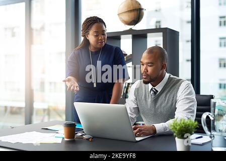 Elle est toujours prête à prêter la main. Une jeune femme d'affaires assiste un collègue de sexe masculin au bureau. Banque D'Images
