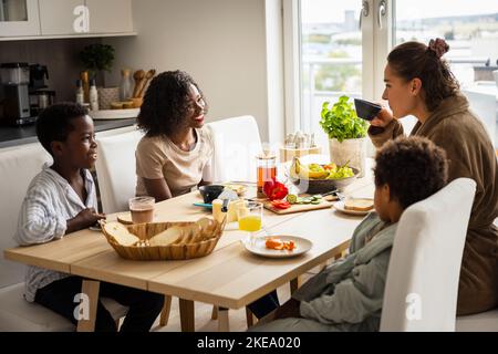 Les mères et les fils mangent le petit-déjeuner Banque D'Images