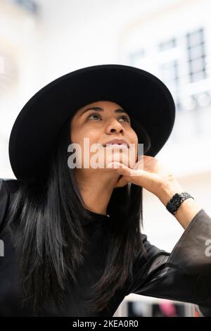 Jeune femme en chapeau noir regardant vers le haut Banque D'Images