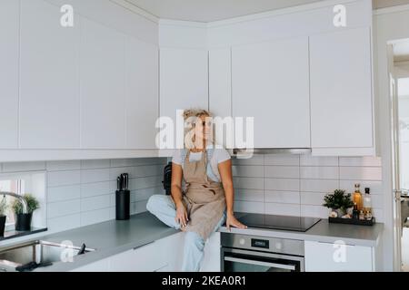 Femme assise dans la cuisine Banque D'Images